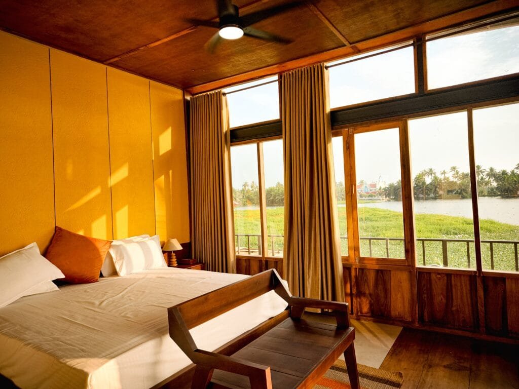Villa bedroom with lake-facing windows at Kyna Backwaters, Kainakary