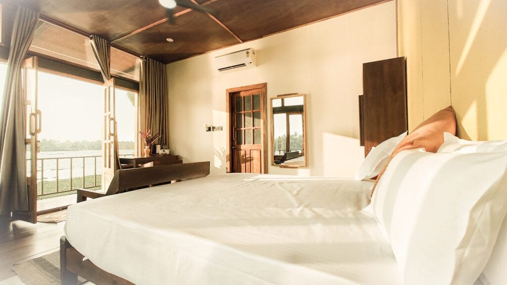 Lake view villa bedroom with king bed and balcony at Kyna Backwaters, Alleppey