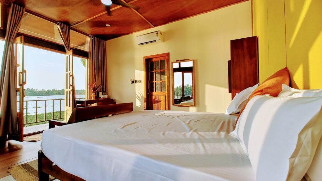 Bright villa bedroom with king bed at Kyna Backwaters resort, Alleppey